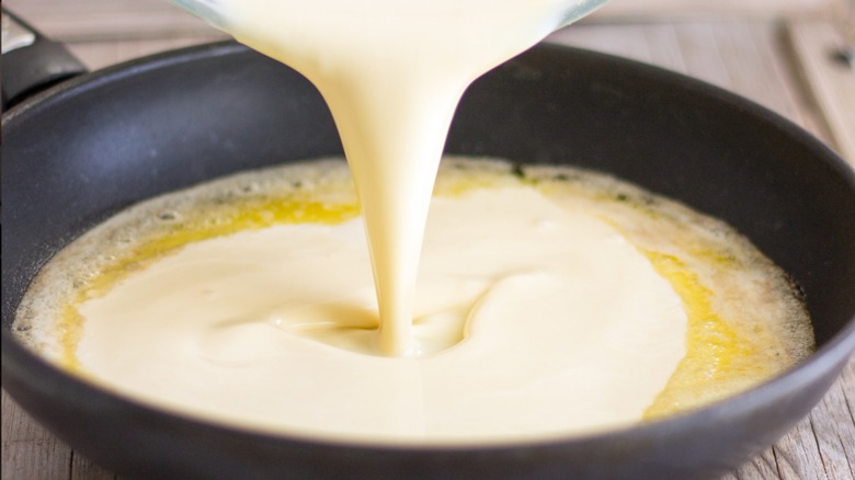 Pouring batter while making Homemade German pancakes or Dutch baby.
