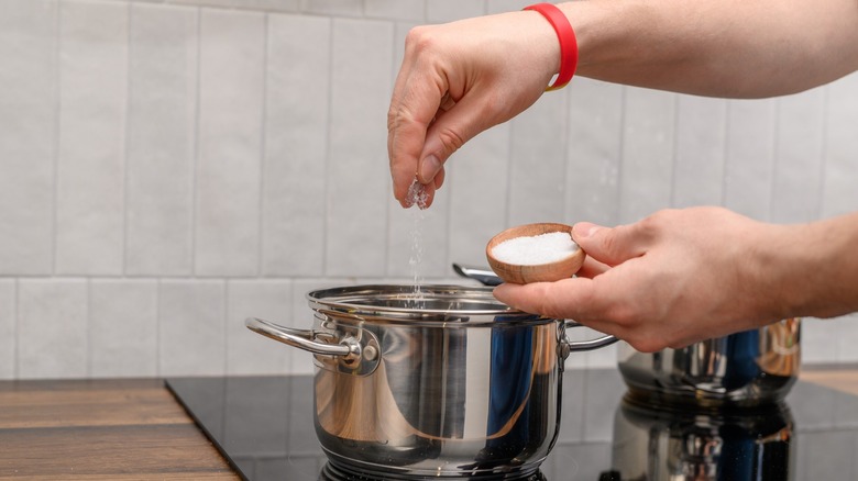 Table salt being added to pot of boiling water