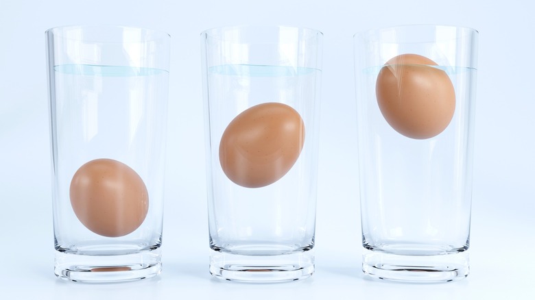 Three glasses containing eggs floating in water