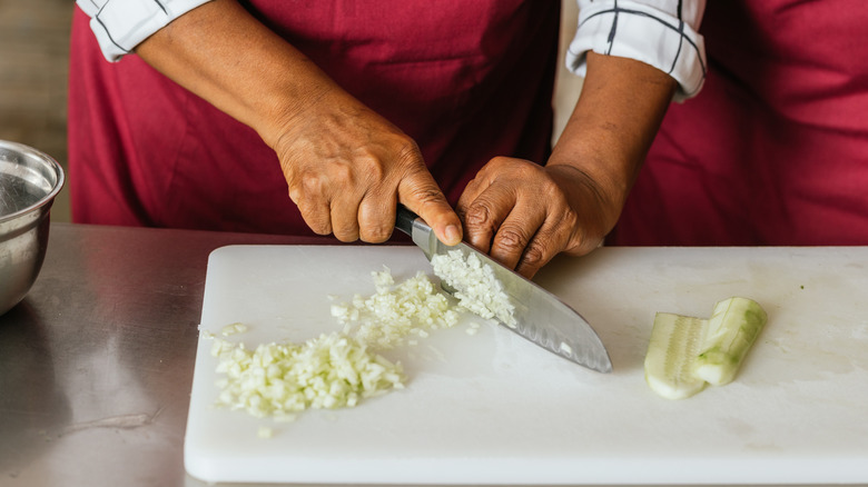 Close-up of a chef's hands skillfully chopping fresh vegetables on a cutting board