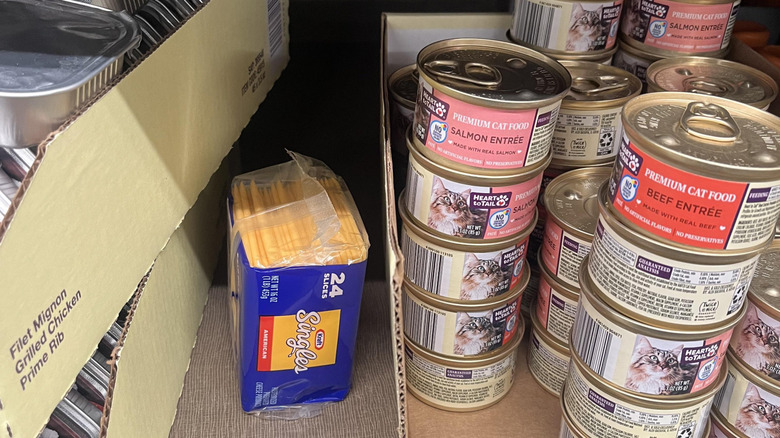 A 24 pack of cheese slices rests between cans in the pet food isle of an Aldi store