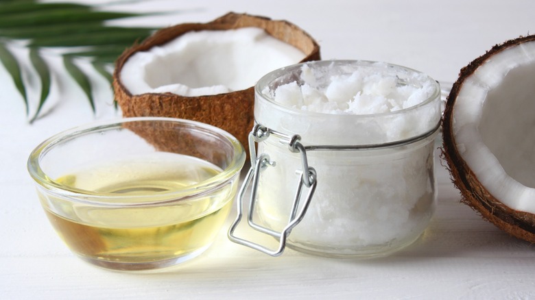 Glass jar and ramekin of coconut oil surrounded by fresh coconut halves