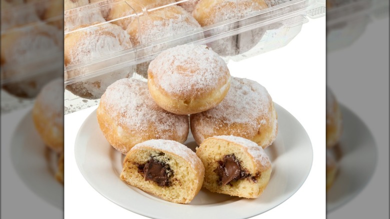 A stack of mini beignets on a white plate in front of a package.