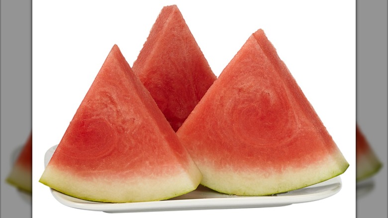 Three seedless watermelon wedges on white plate on white background