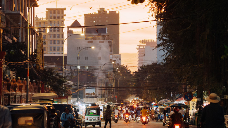 Busy street with motorbikes, tuk tuks, and pedestrians in Phnom Penh, Cambodia
