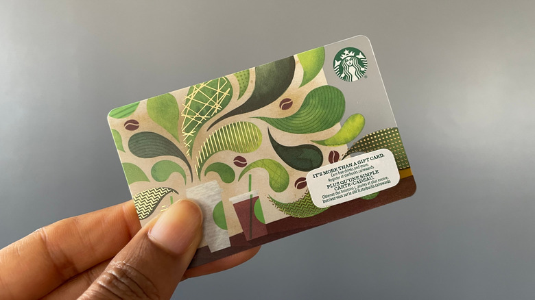 Hand holding a gift card from Starbucks