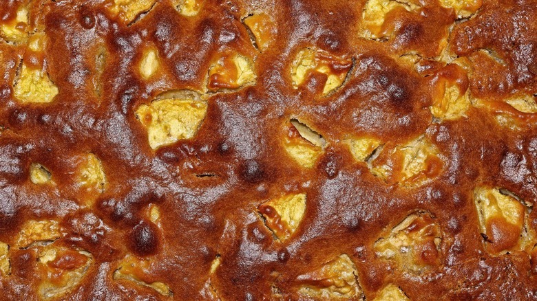 A close-up, overhead shot of an apple whiskey pandowdy, featuring pastry around baked fruit.