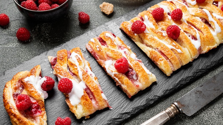 A delicious cheesecake pastry made with puffed pastry, and raspberry jam, styled with fresh raspberries.