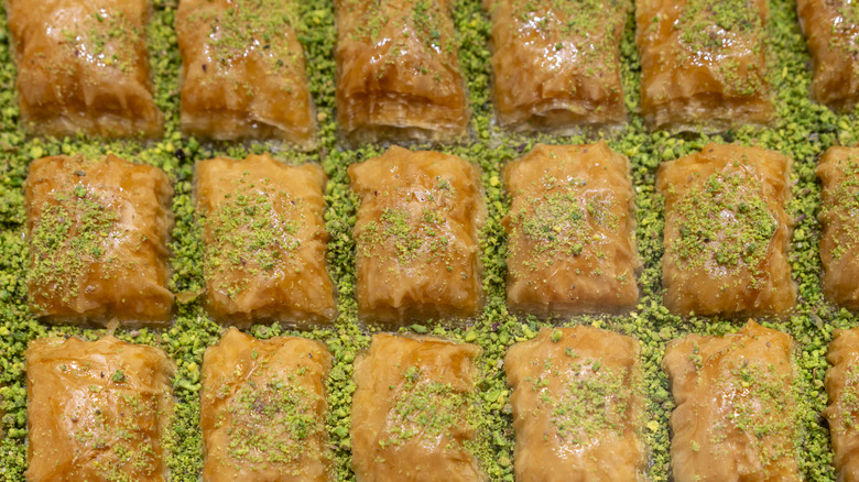 An overhead shot of baklava squares surrounded by crushed pistachios.