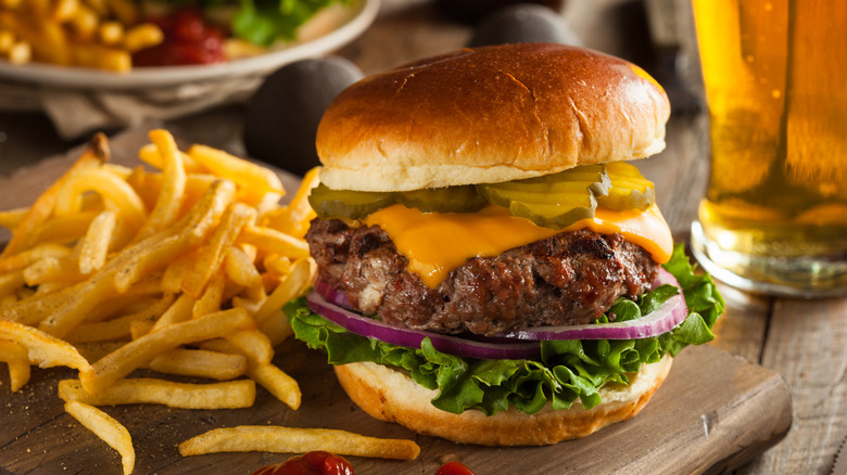 greasy fries next to a burger and beer