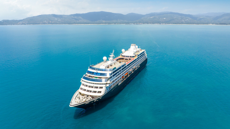 cruise ship in the middle of the sea with mountains behind