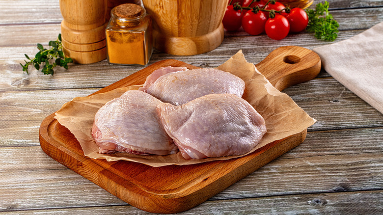 Raw chicken thighs for cooking over board