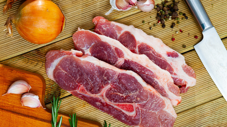 Cooking raw pork shoulder on wooden kitchen table
