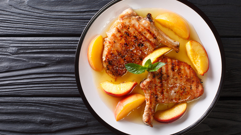 A plate of grilled pork chops with glazed peaches and honey garlic sauce