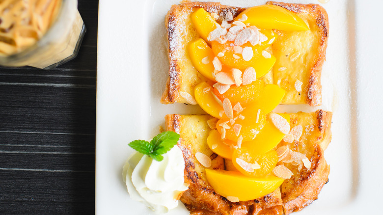 A plate of bread pudding topped with peach slices, mandarin oranges, and slivered almonds