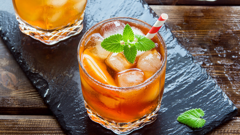 Glasses of sweet ice tea with peach slices, mint ,and ice on a table