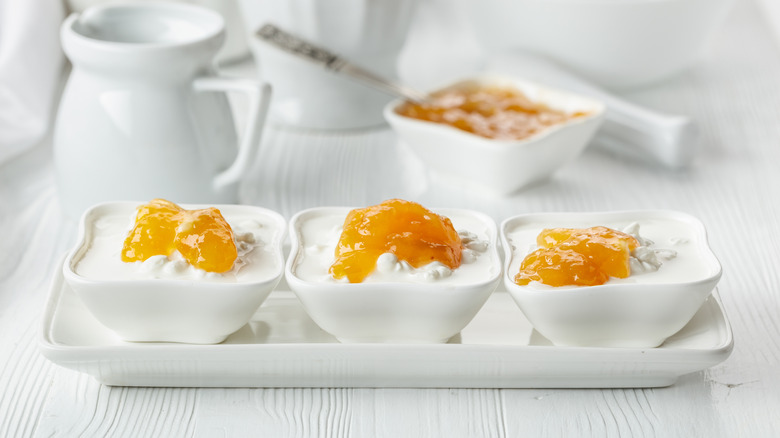 Several bowls of cottage cheese with peach topping on a white table