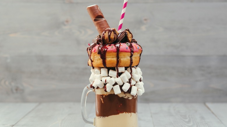 An elaborate milkshake that contains a donut.
