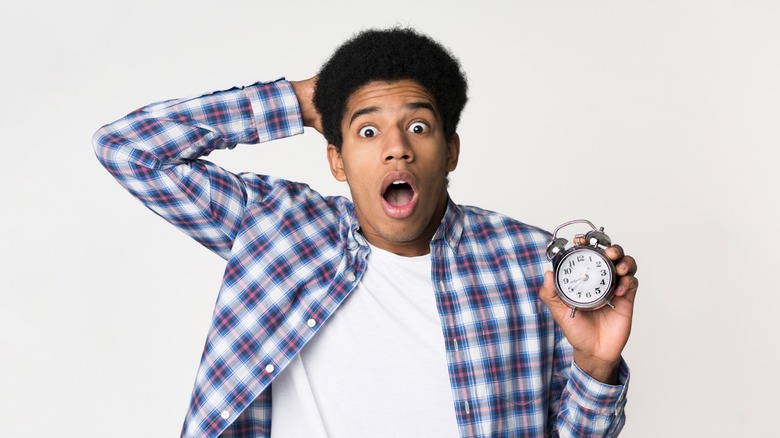 Guy holding a clock with a shocked look on his face