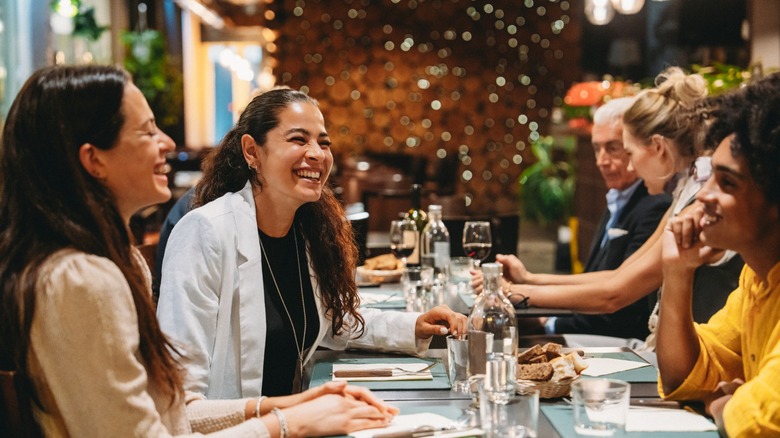 Group of friends laughing and enjoying dinner together at a restaurant, celebrating and having fun