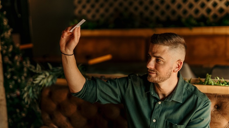 A man sitting in a bright restaurant and calling a waiter for a check