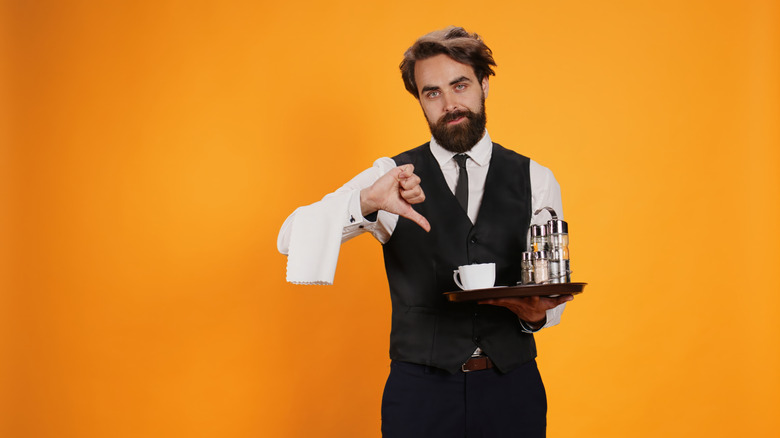 Server holding a tray and giving a thumbs down sign