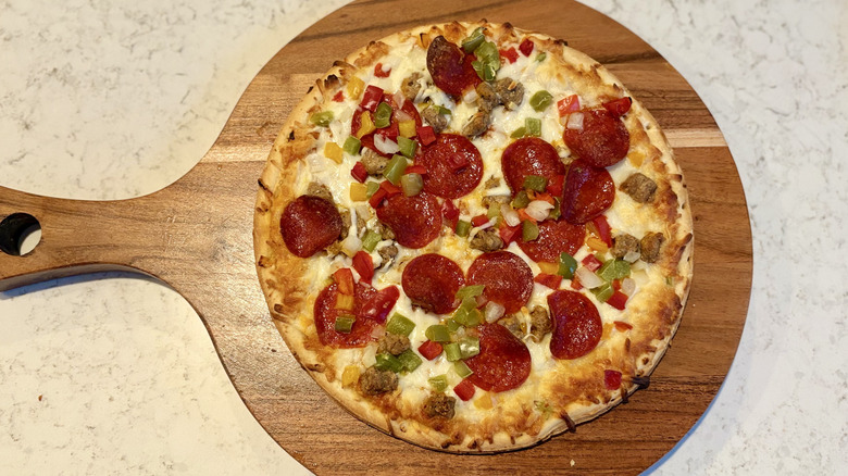 DiGiorno classic thin crust supreme pizza on a wood cutting board