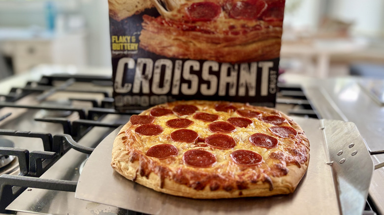 A baked DiGiorno croissant crust pizza on a pizza peel