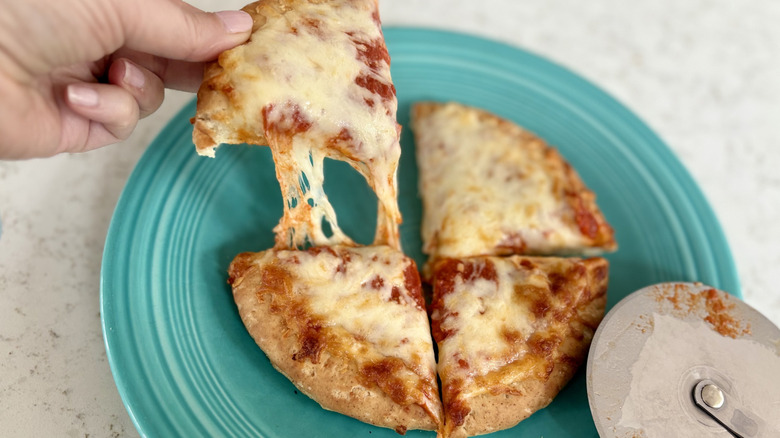 A hand pulls a piece of cheesy hand-tossed DiGiorno pizza