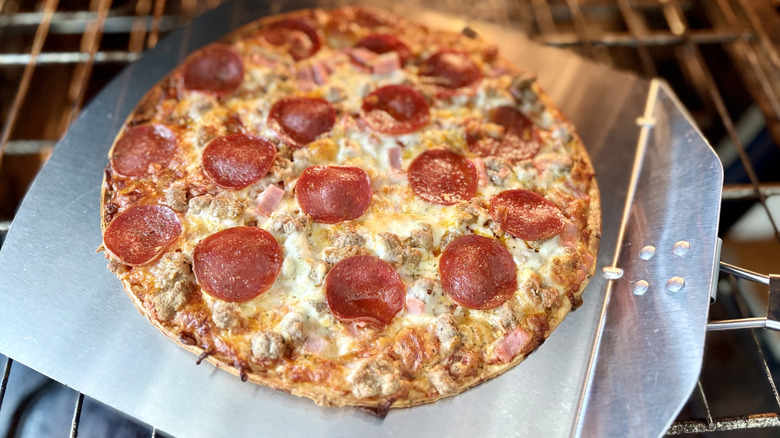A loaded ultra thin crust carnivore pizza comes out of the oven