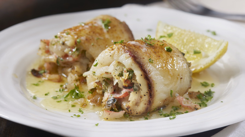 A prepared dish of fish stuffed with crab on a plate with lemon