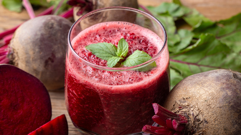 A glass of fresh beet juice topped  with a green herb