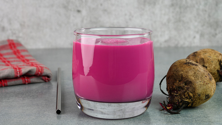 Beet smoothie in a glass next to whole beets