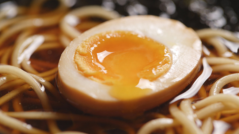 A soft-boiled ramen egg with a jammy yolk resting atop noodles