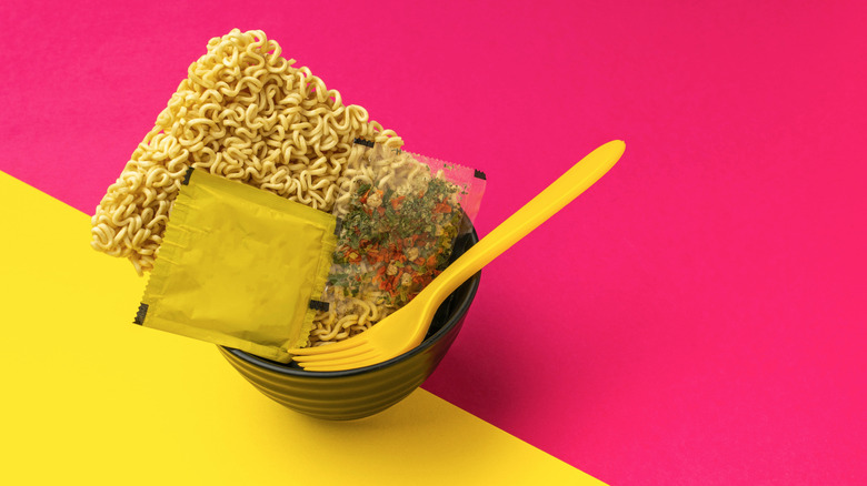 Instant ramen noodles and seasoning in bowl with fork
