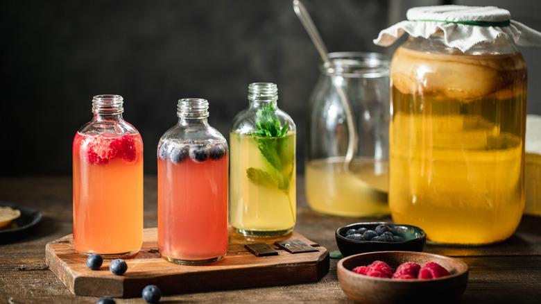 Three different flavored kombucha tea bottles in the kitchen with ingredients on wooden table