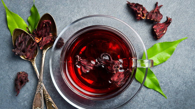 Close-up of a cup of red hibiscus tea in a glass with flowers