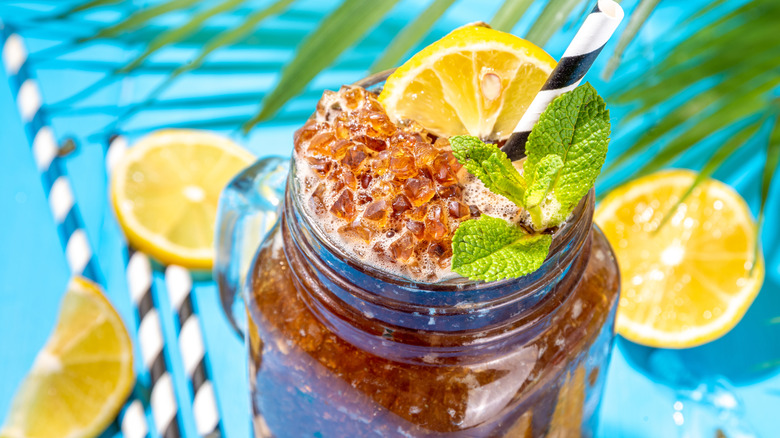 Slushy iced tea in a mason jar garnished with lemon slices and fresh mint