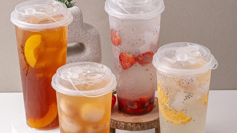 Peach iced tea, lychee iced tea, strawberry iced tea, and lemon iced tea, served on a table with a white base
