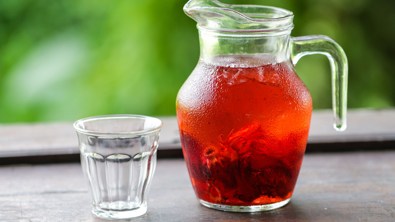 Chilled Roselle Hibiscus Tea in Glass Pitcher with Empty Cup