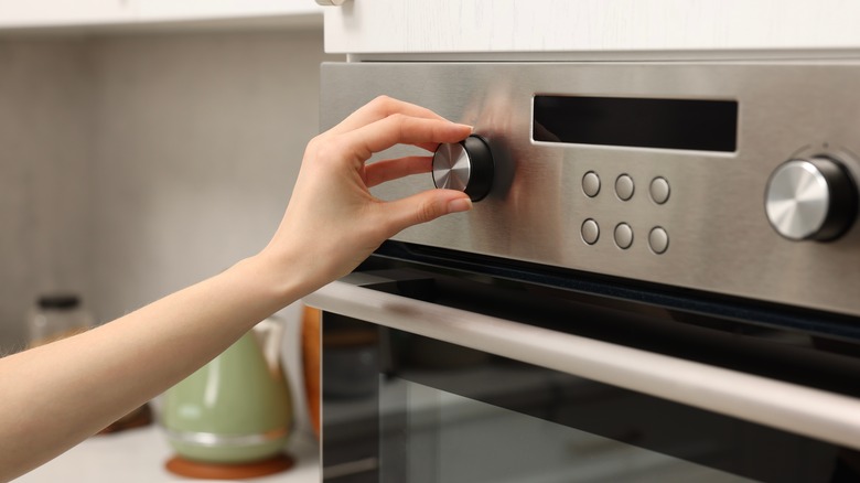 Person adjusting dial on the oven