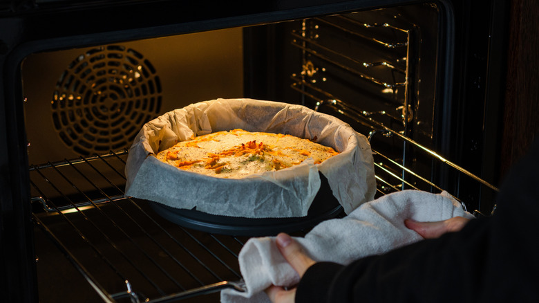 A freshly-baked cheesecake being removed from a convection oven