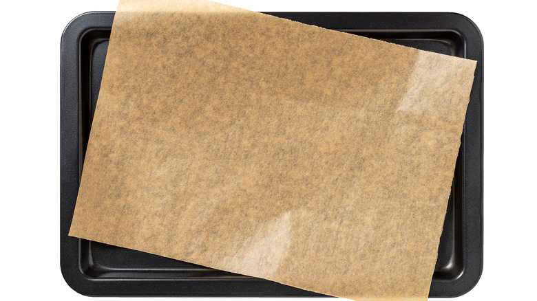 Baking tray against a white background with a sheet of parchment paper on top