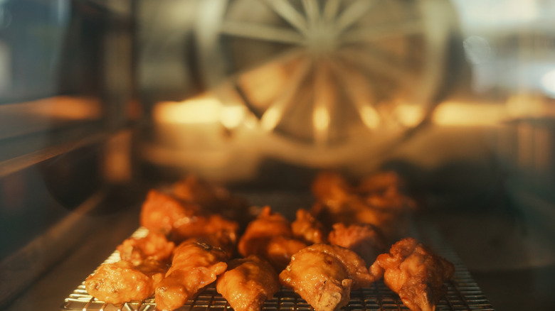 Chicken wings roasting on a wire rack inside an convection oven