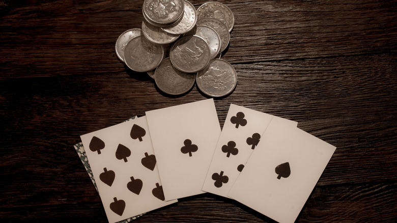A poker hand laid on the table, a stack of coins resting above.