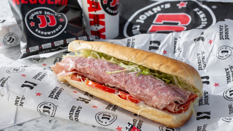 Jimmy John's sandwich on the brand's wrapping with chips and a drink in the background.