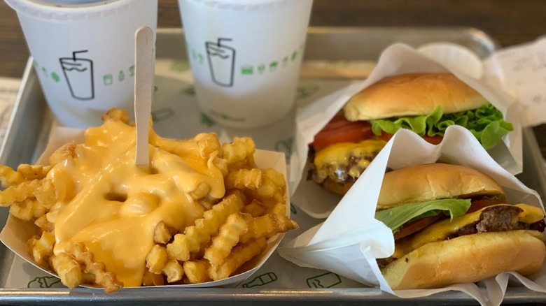Shake Shack burgers and cheese fries sitting on a metal tray.