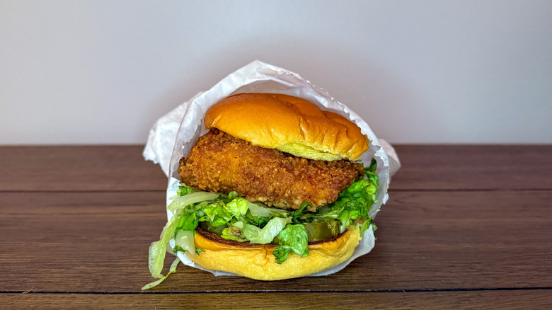 Shake Shack's fried chicken sandwich in wrapper on wooden table