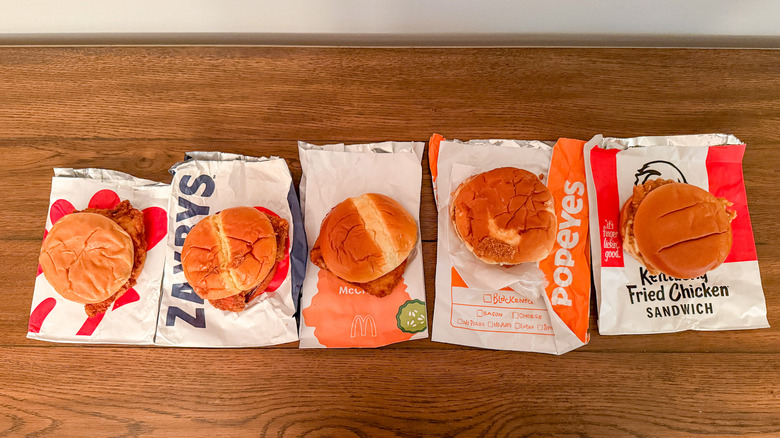 Selection of fast-food fried chicken sandwiches lined up on a wooden table