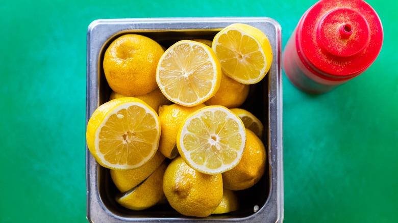 Lemons on Green Background in Square Metal Container and plastic red bottle of ketchup